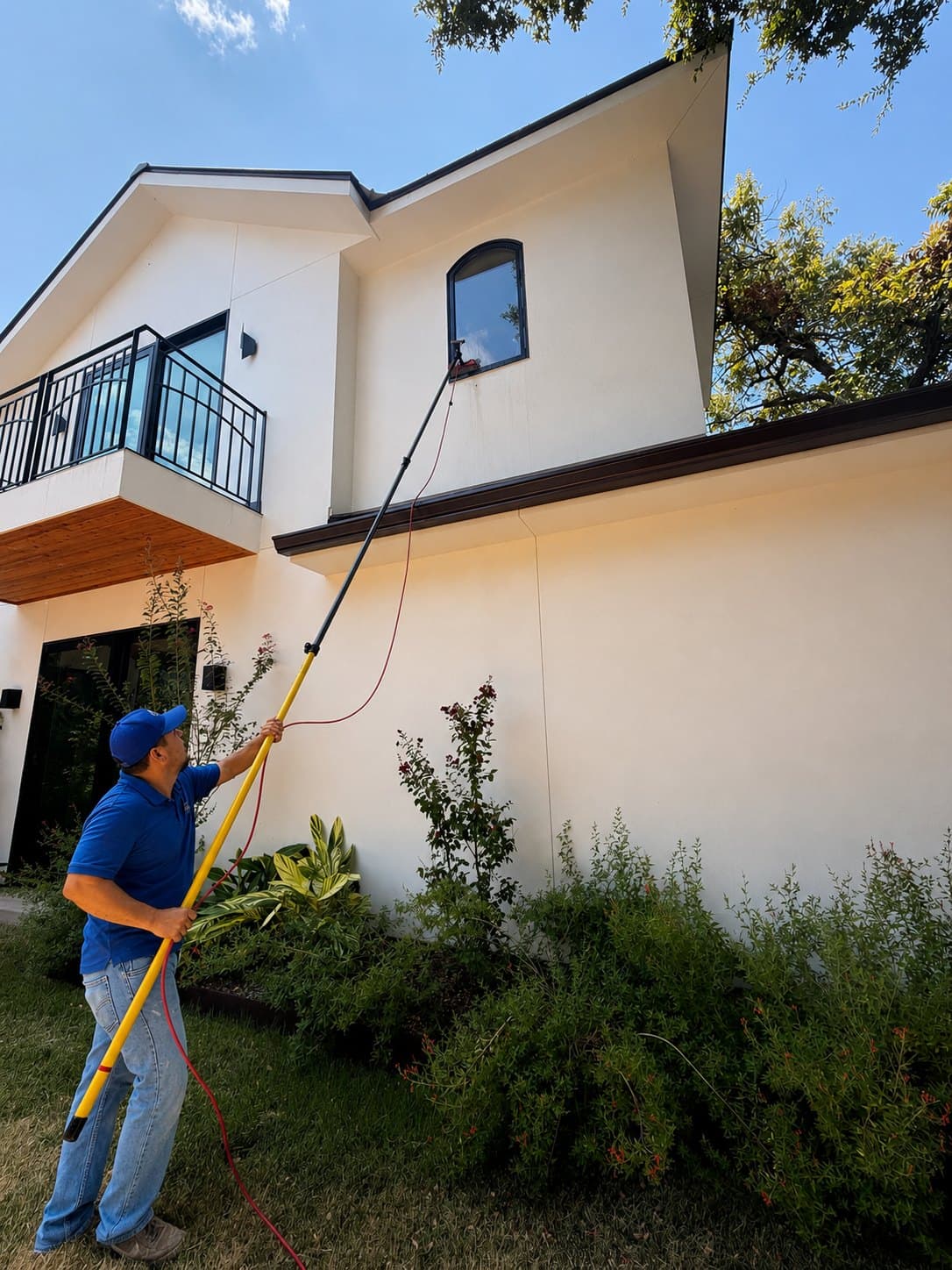 Window cleaning on a brick home with a water-fed pole